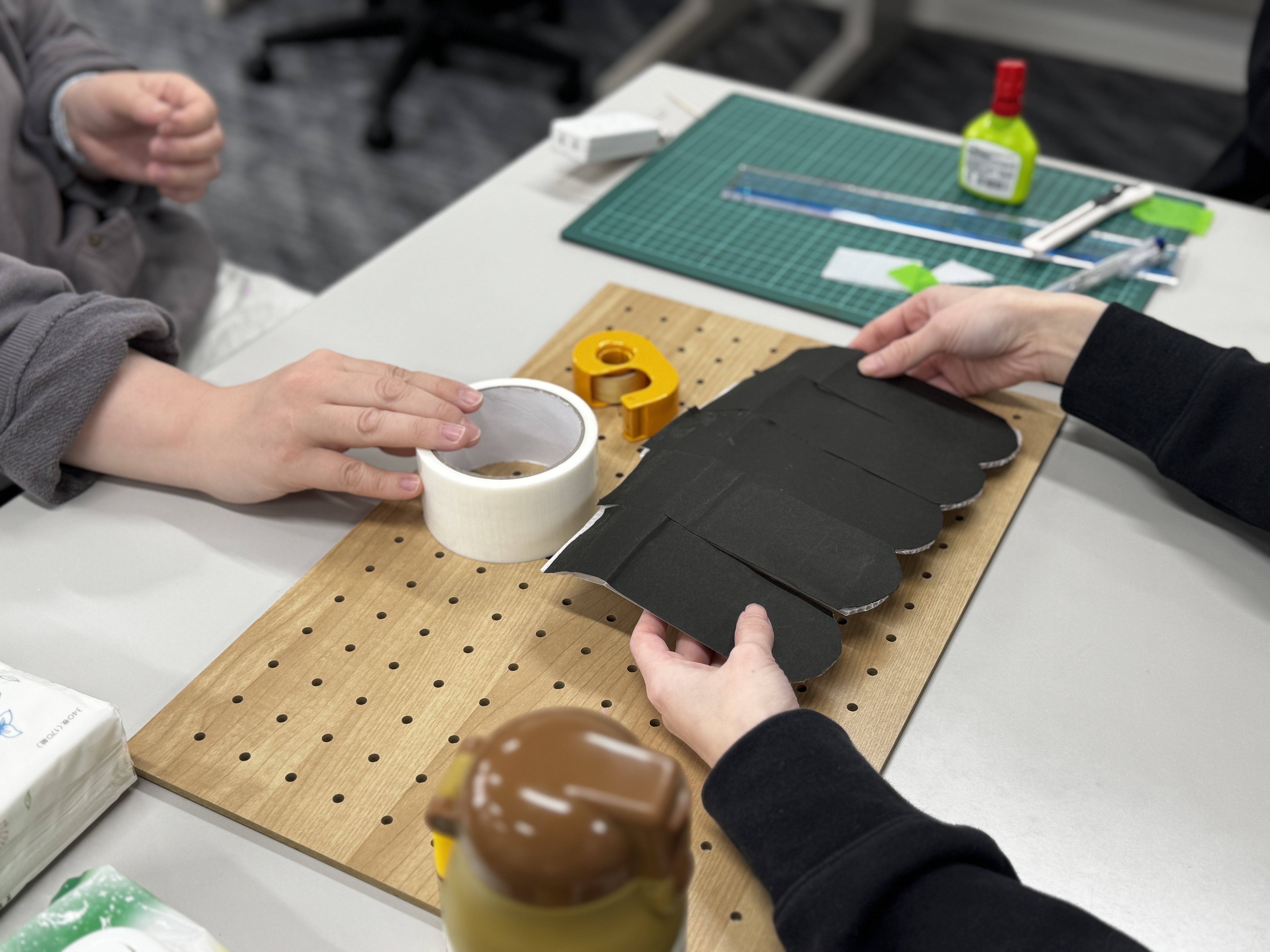 ペグボードにテープを貼りながらブースの土台を制作している様子
