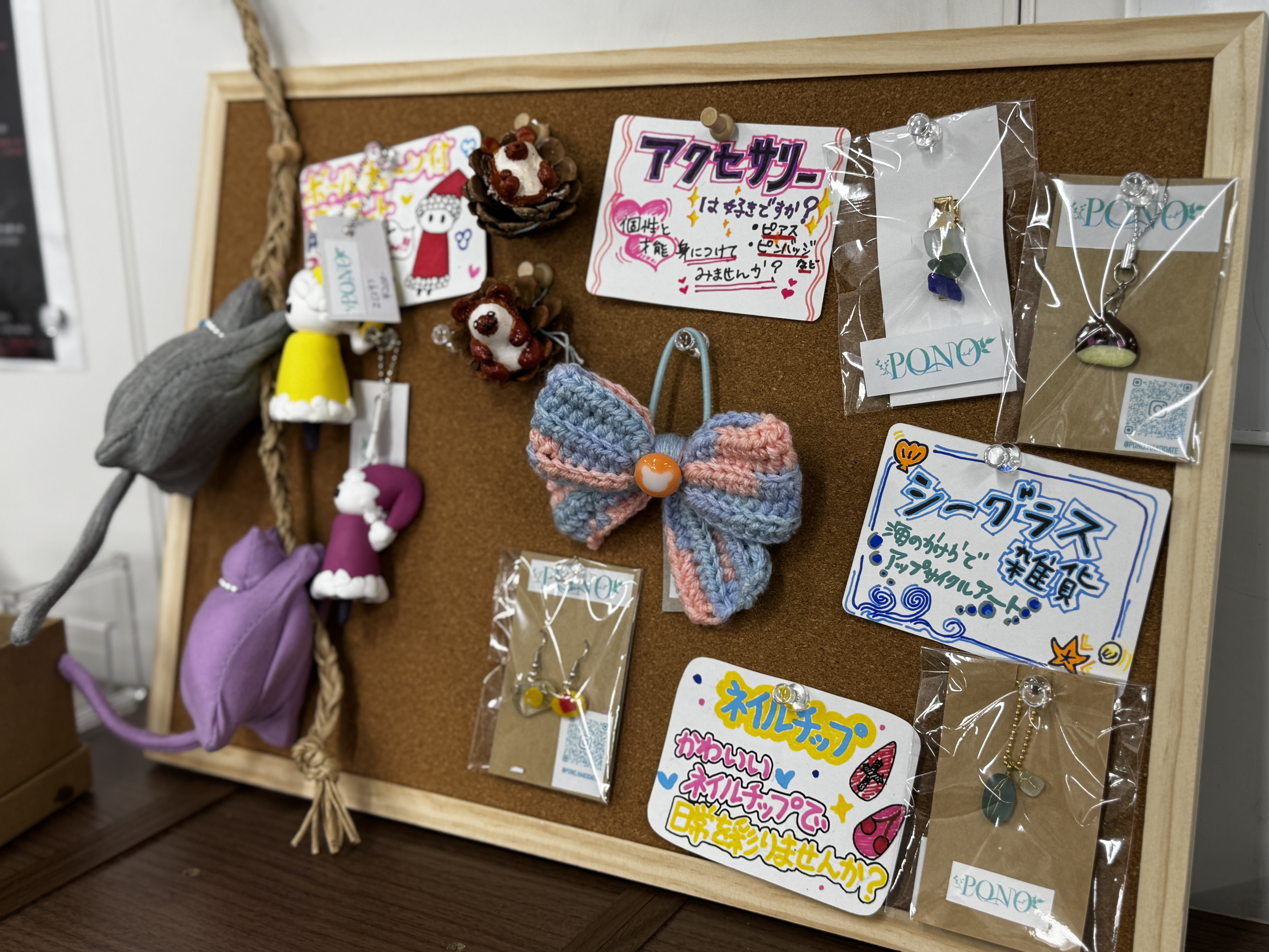 コルクボードに並ぶアクセサリーや編み物リボン、シーグラス雑貨などのハンドメイド作品