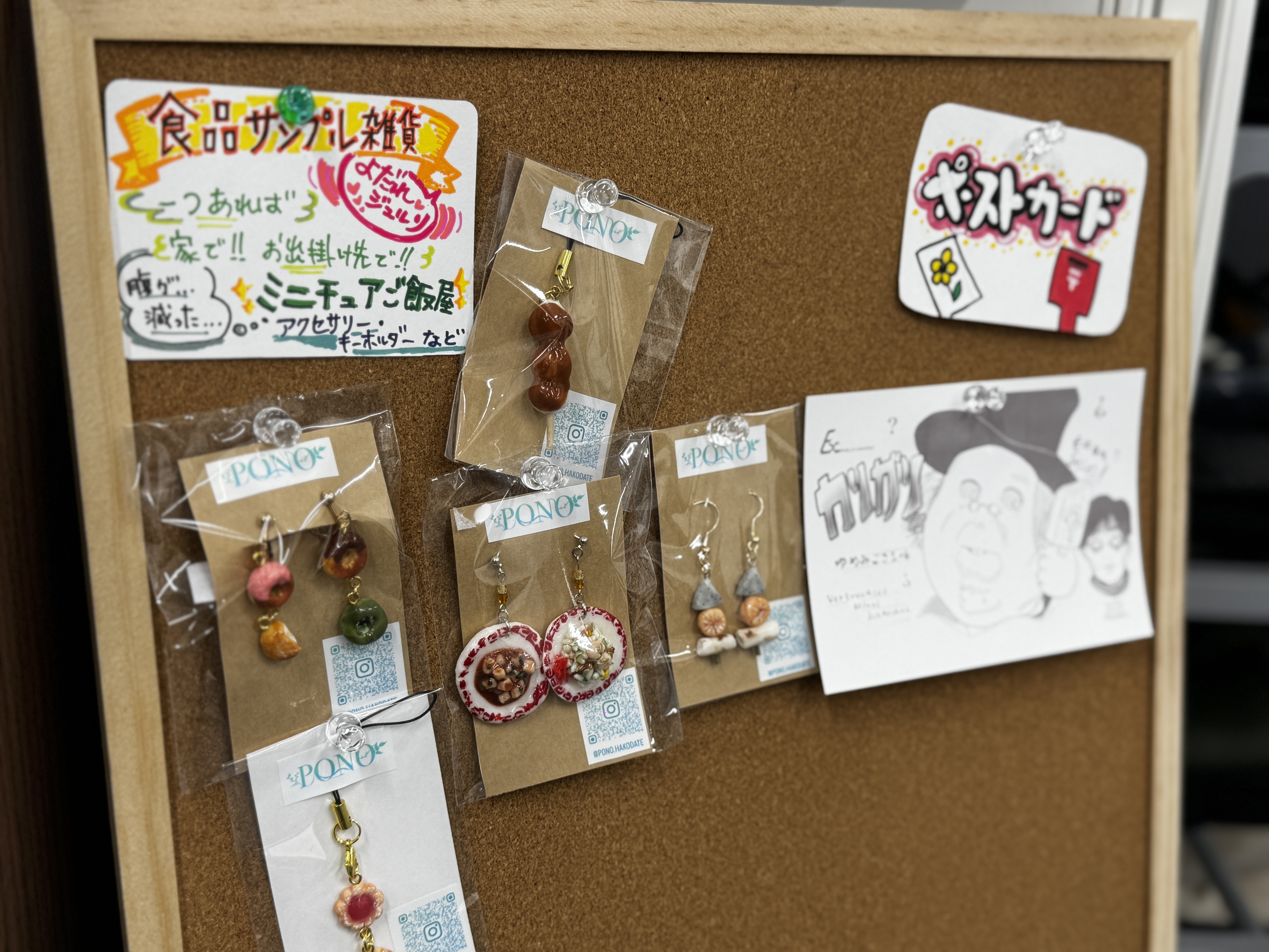 食品サンプルのアクセサリーやミニチュア飯屋、ポストカードなどが並ぶコルクボード