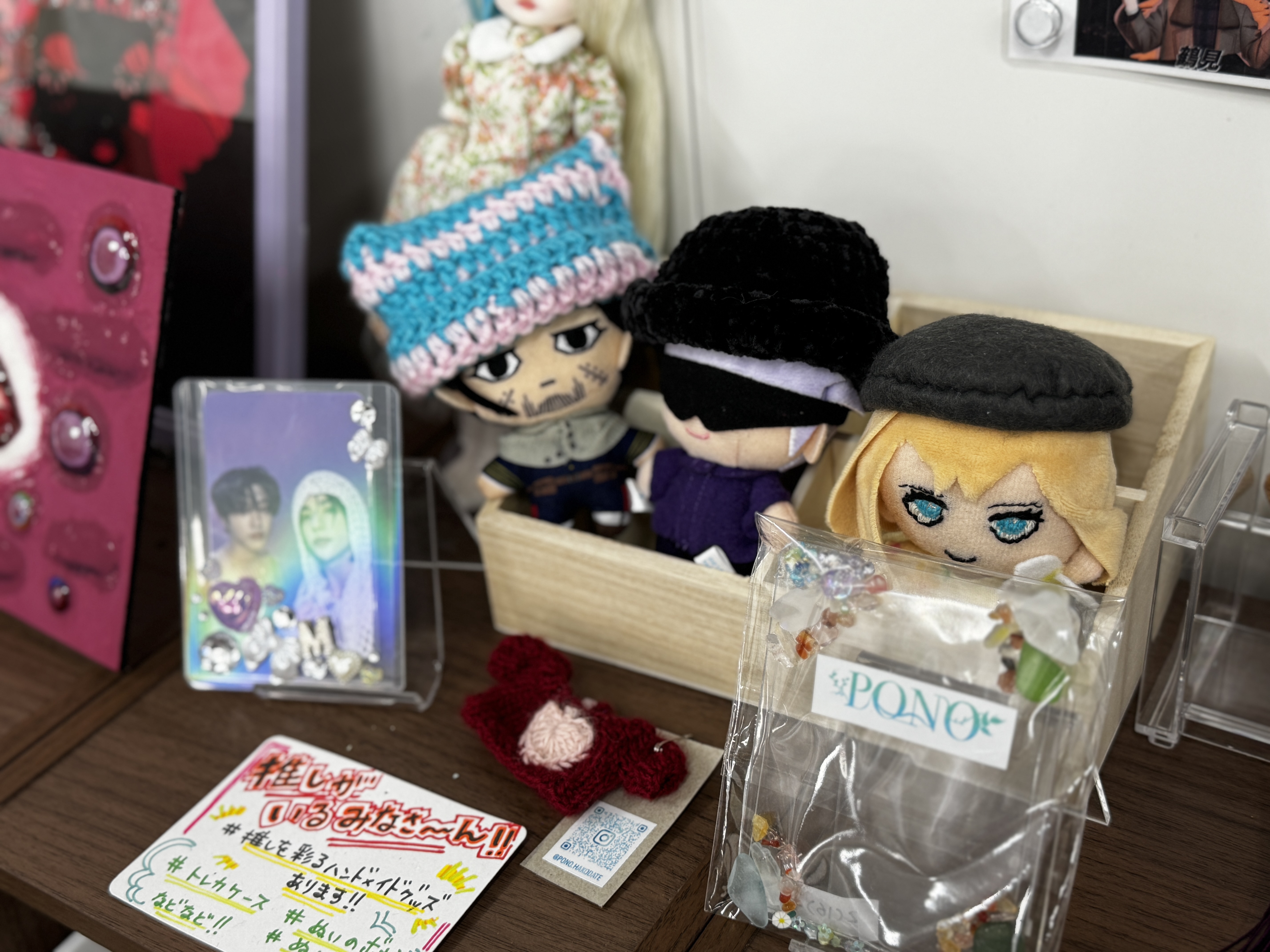 手編みの帽子をかぶったぬいぐるみやビーズアクセサリーが飾られた棚