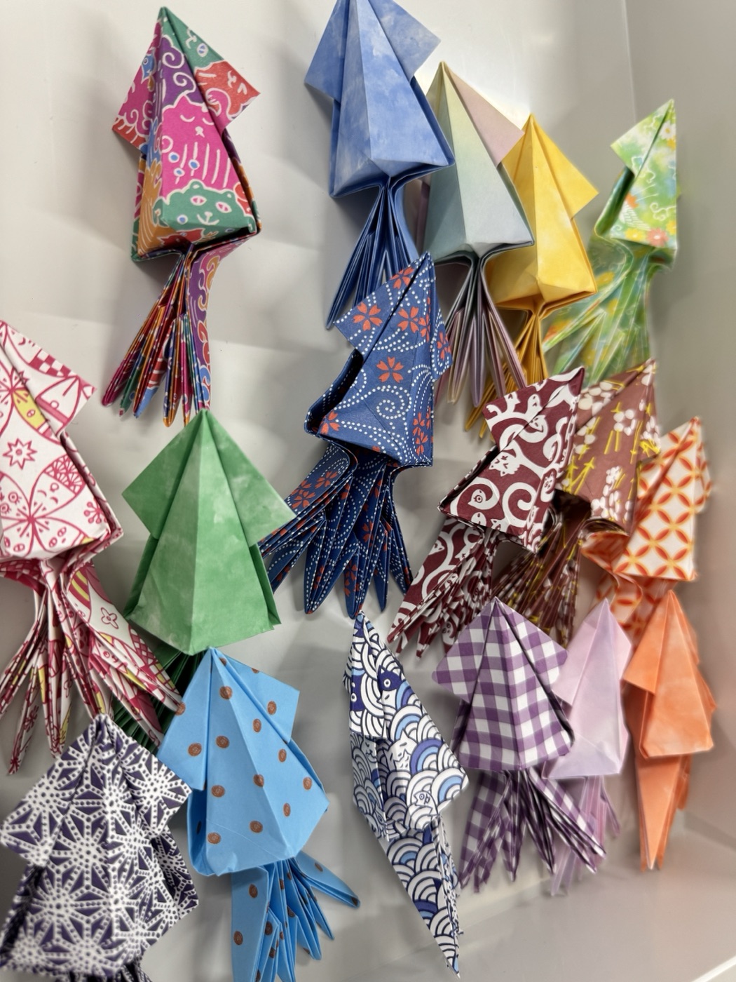 色や柄のちがう折り紙で作られたたくさんの「イカ」の作品。ご来場プレゼント用に手づくりされたもの