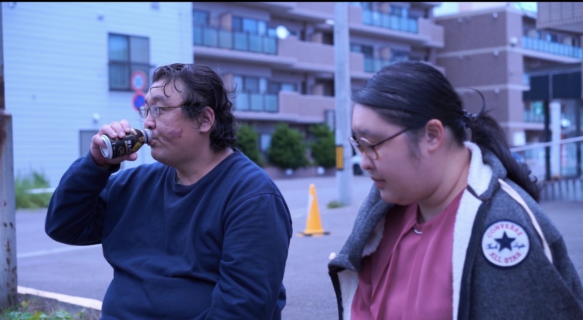 完成したショートムービーのワンシーン。屋外で利用者さん2人が並んで演技している場面