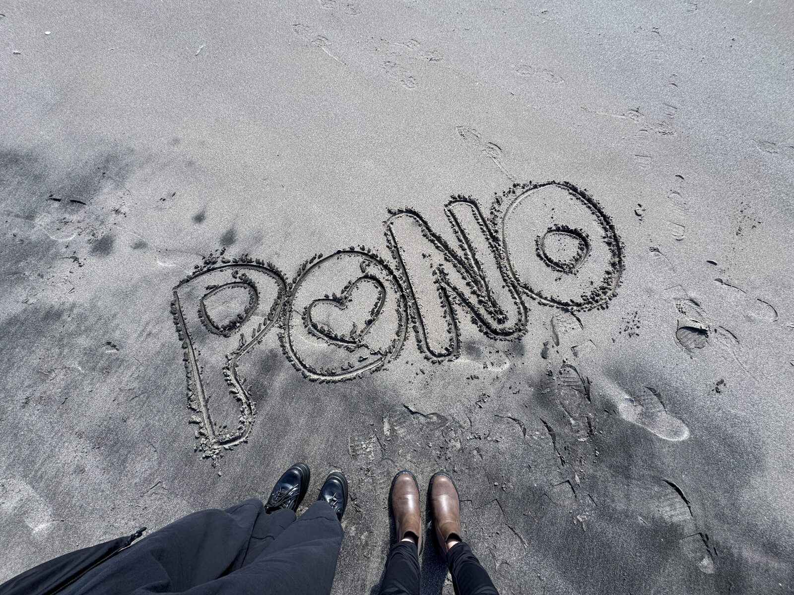 砂浜にハート入りで描かれた「PONO」の文字と、利用者さんたちの足元